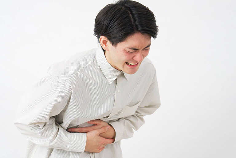 下腹部を抑え痛がる男性