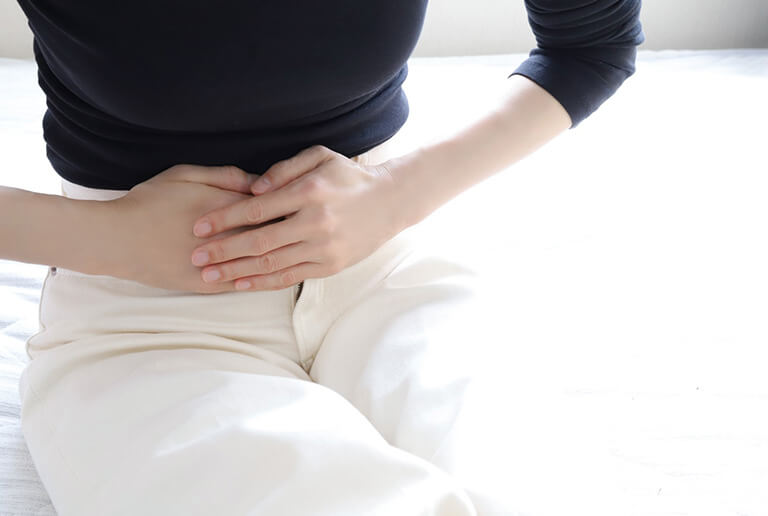 下腹部を抑えて座る女性